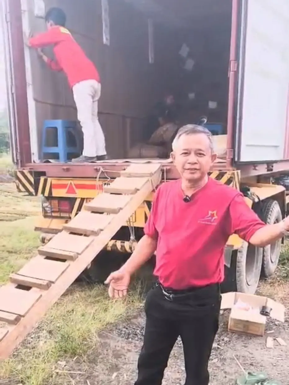 A supervisor overseeing the loading of goods into an international shipping container at an export site.
