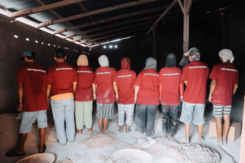 A line of production staff in red uniforms standing in a processing facility, showcasing the scale of the natural resin workforce.